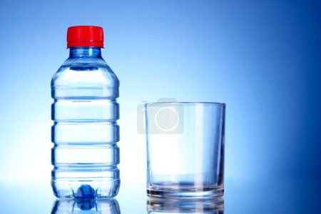 Bouteille d'eau et de verre sur fond bleu 