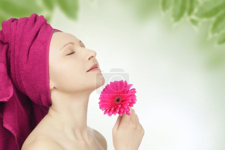 Jeune femme avec serviette et fleur de gerbera 